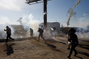 Migrants, part of a caravan of thousands traveling from Central America en route to the United States, and journalists flee tear gas released by U.S. border patrol near the fence between Mexico and the United States in Tijuana