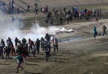 U.S. Border Patrol Launches Tear Gas At Migrants Over Attempt To Breach Fence Migrants